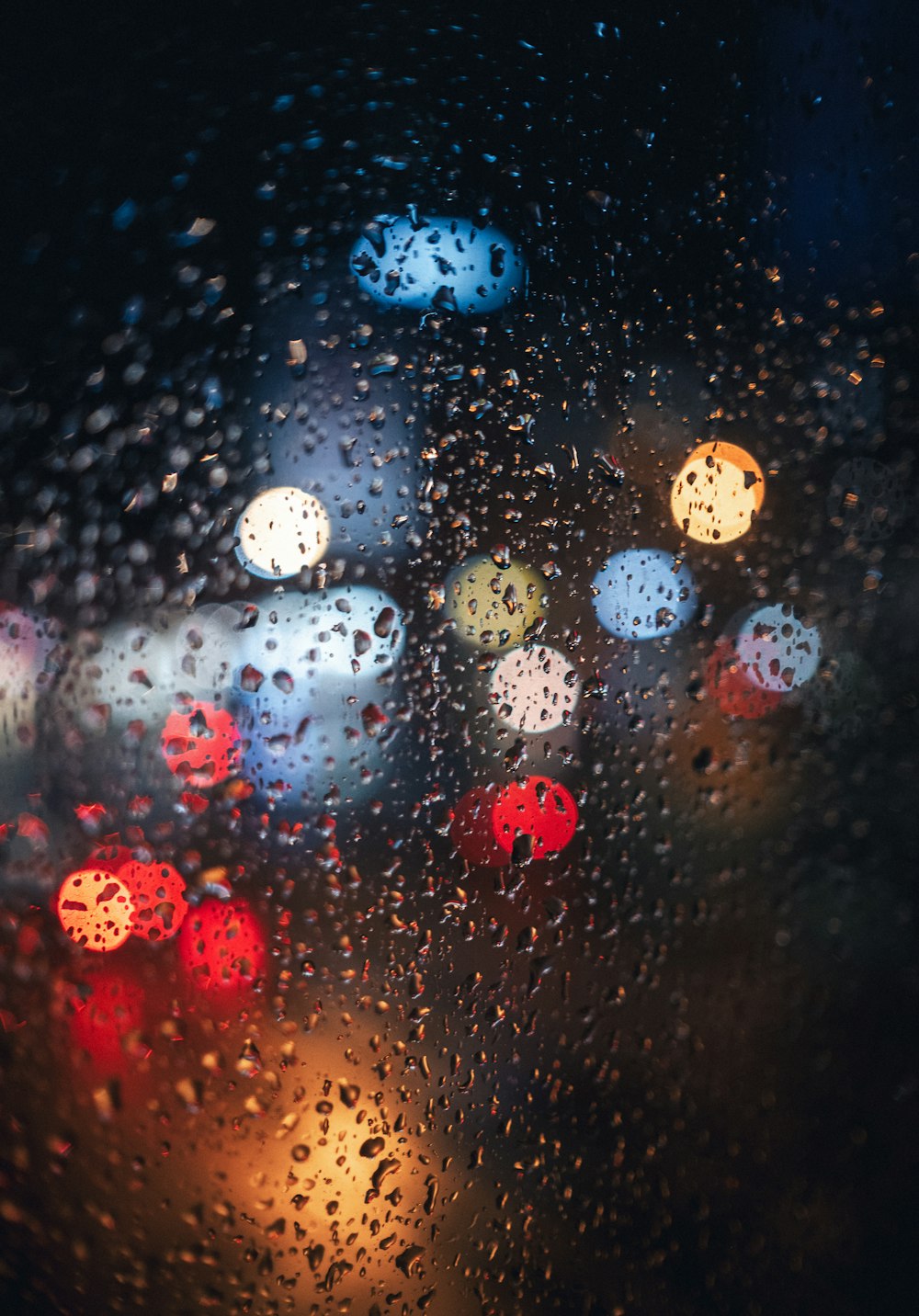 une image floue de feux de circulation à travers une fenêtre couverte de pluie