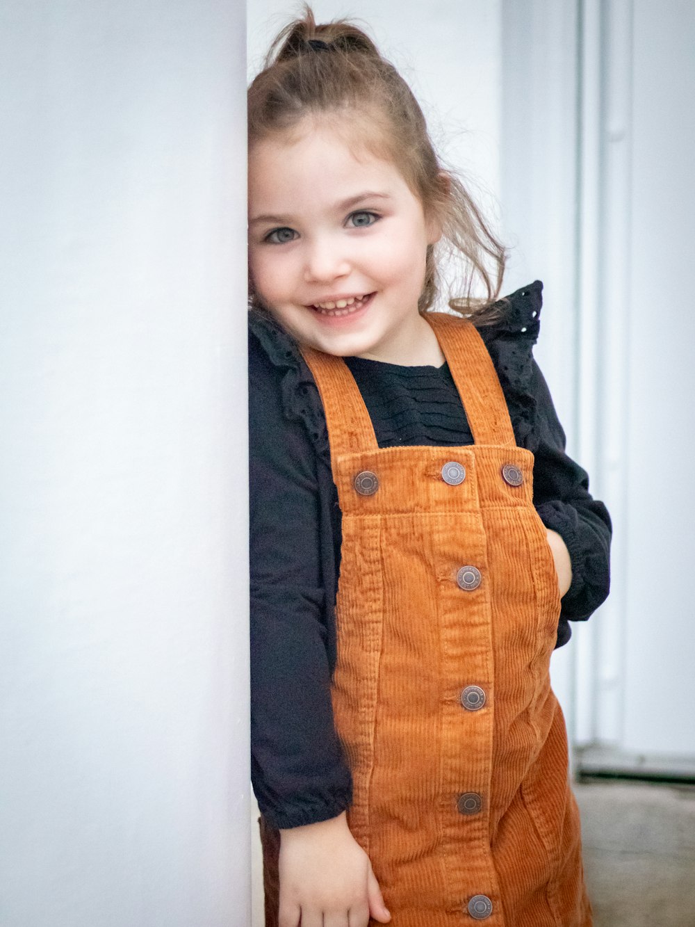 a little girl that is leaning against a wall