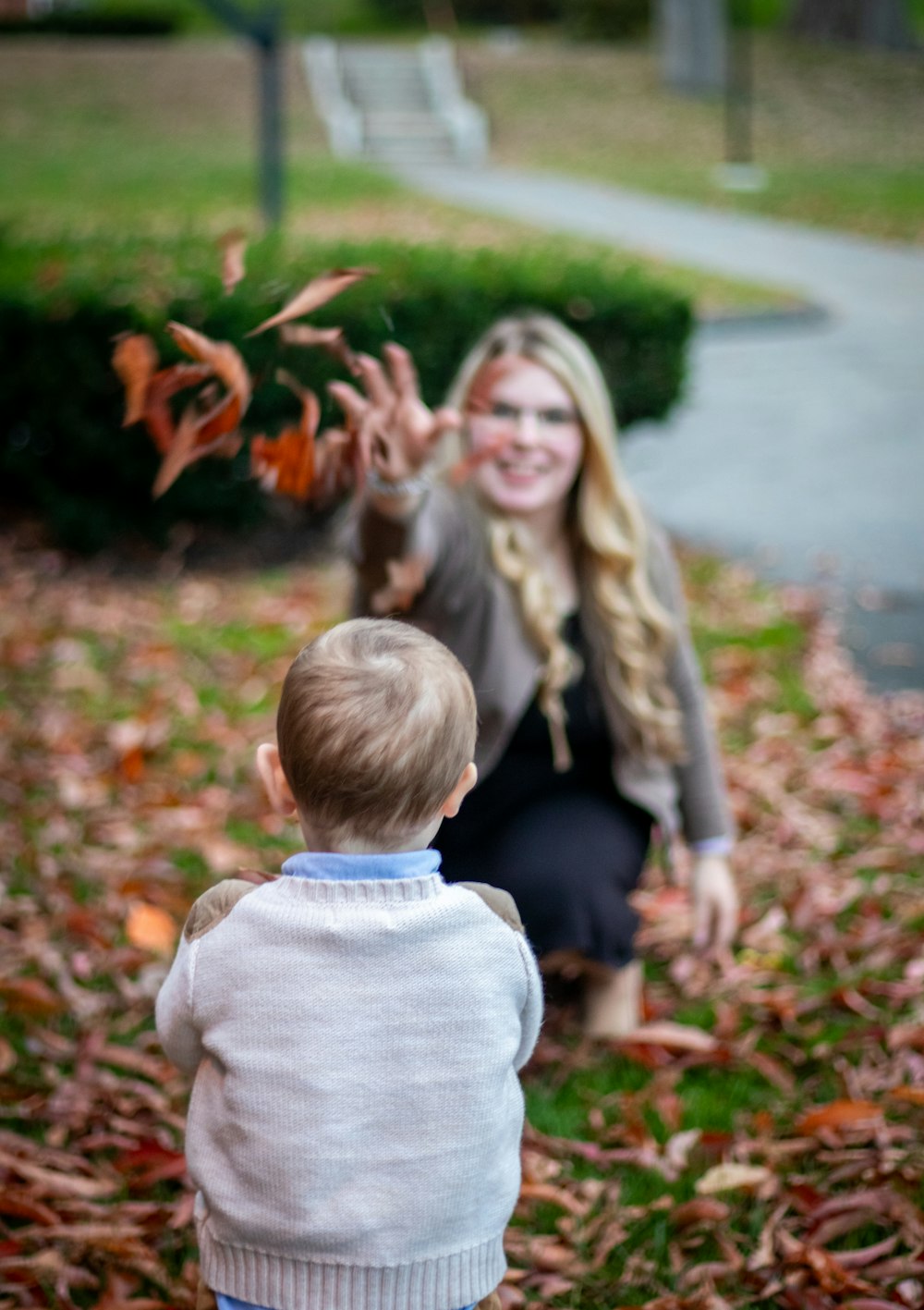 a woman kneeling down next to a little boy