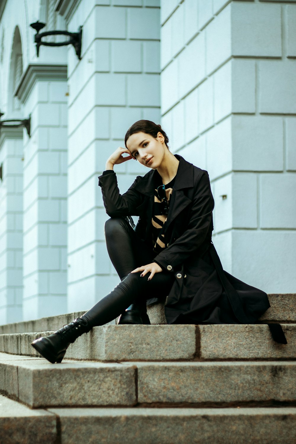 a woman is sitting on the steps of a building