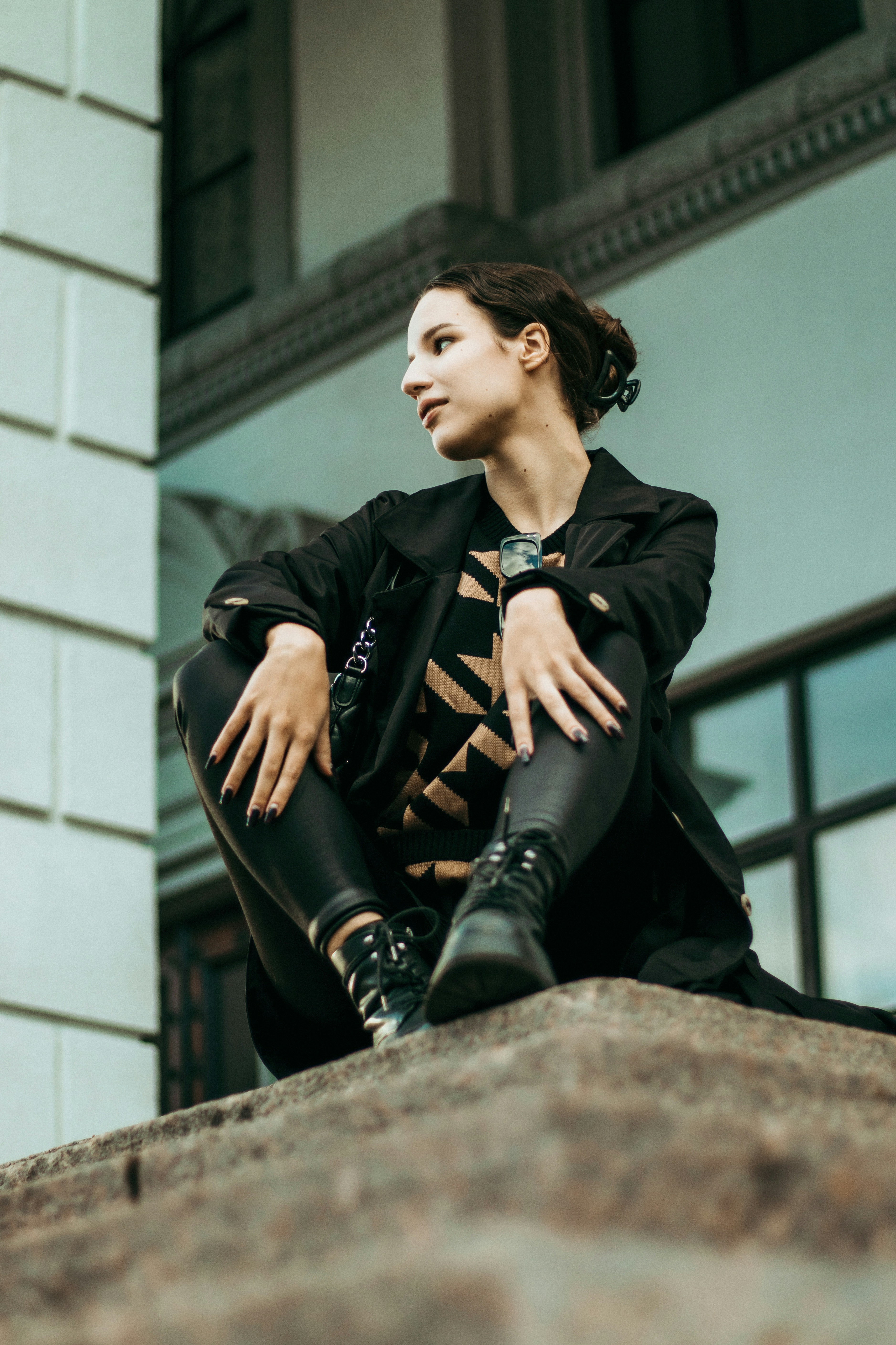 una donna seduta in cima a un muro di pietra accanto a un edificio