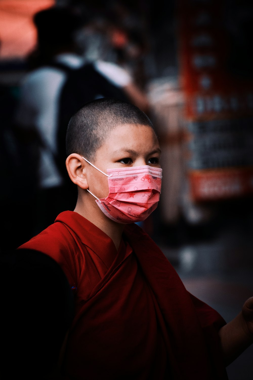 a young boy wearing a face mask on a street