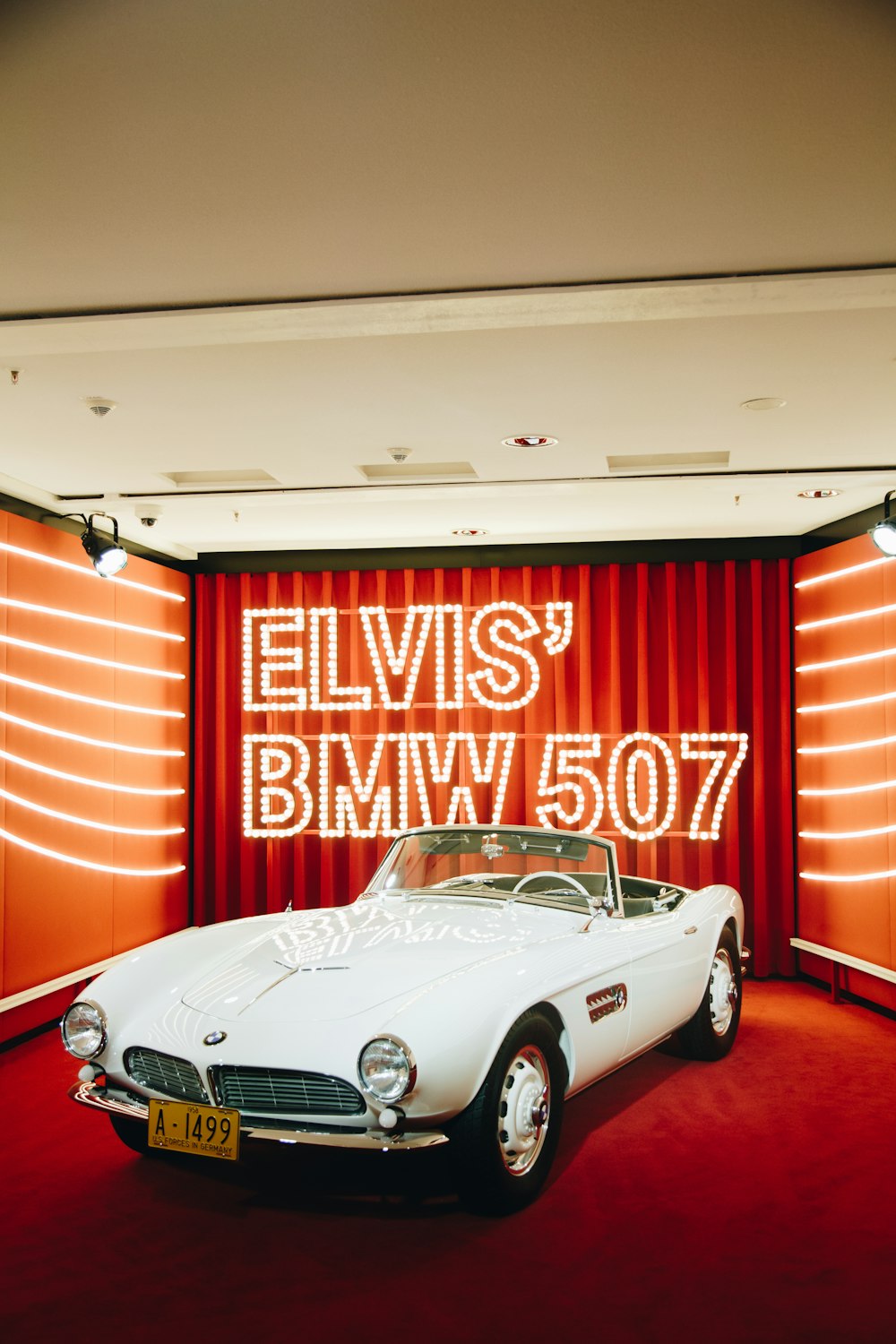 a white sports car parked in front of a red curtain