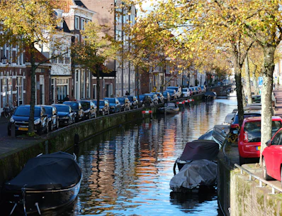 A sleek taxi parked by an iconic Amsterdam canal at sunset.