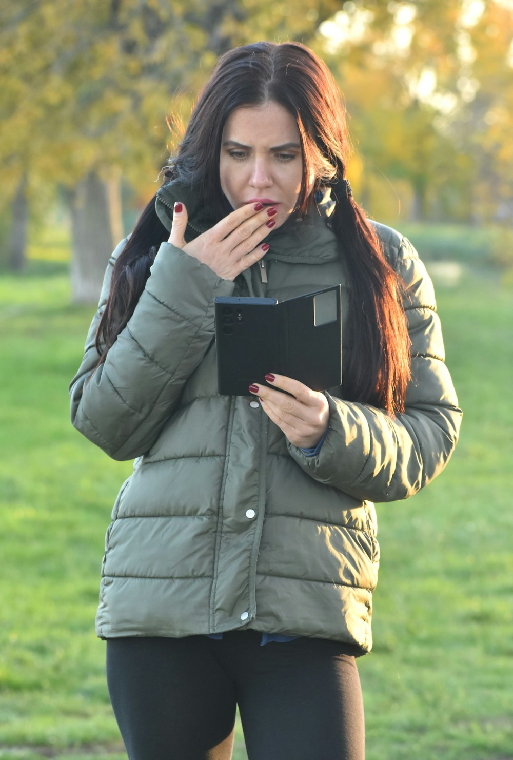 a woman standing in a park holding a tablet