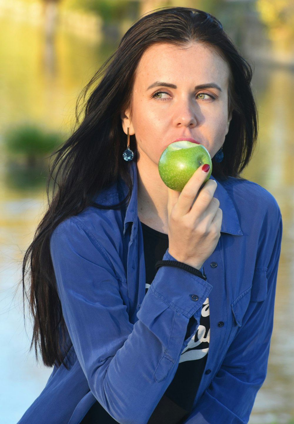 una mujer con camisa azul comiendo una manzana