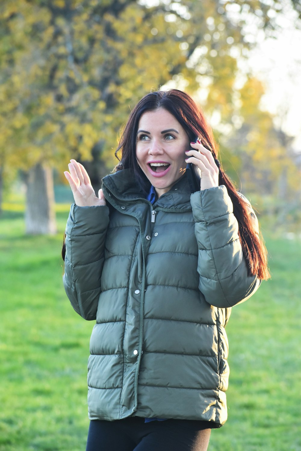 eine Frau in einem Park, die mit einem Handy telefoniert