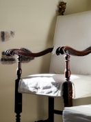 a chair with a wooden arm rests against a wall
