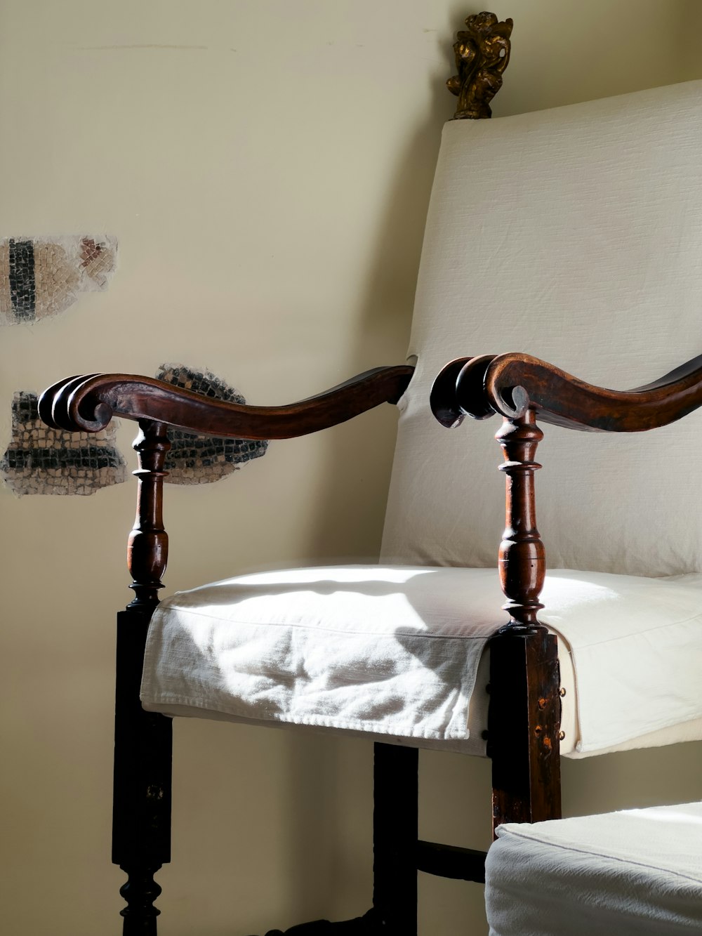 a chair with a wooden arm rests against a wall