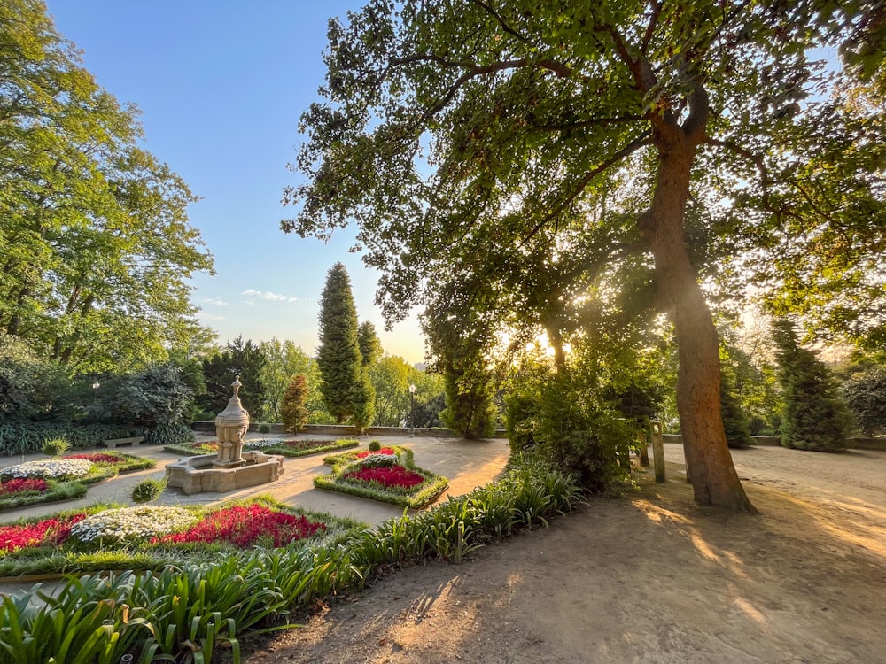 a garden with a fountain surrounded by trees and flowers