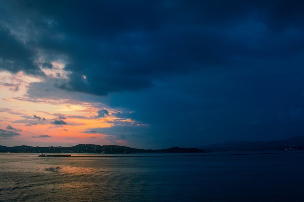 a boat floating on top of a large body of water under a cloudy sky