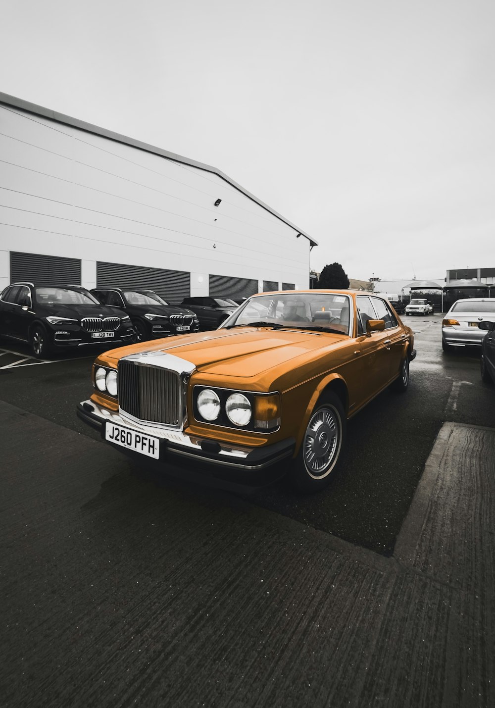 a yellow car parked in a parking lot next to other cars