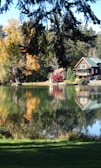 a lake surrounded by trees with a house in the background