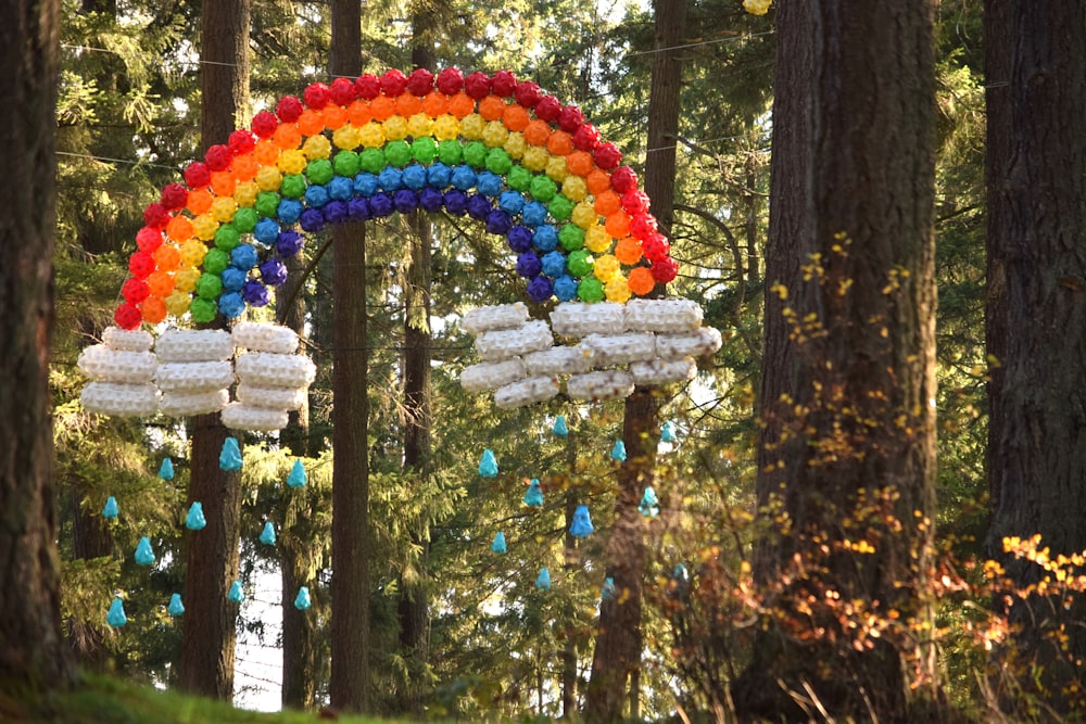 a rainbow decoration hanging from a tree in a forest