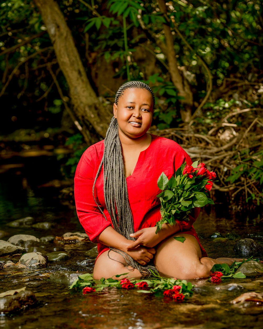 a woman in a red shirt is sitting in a stream