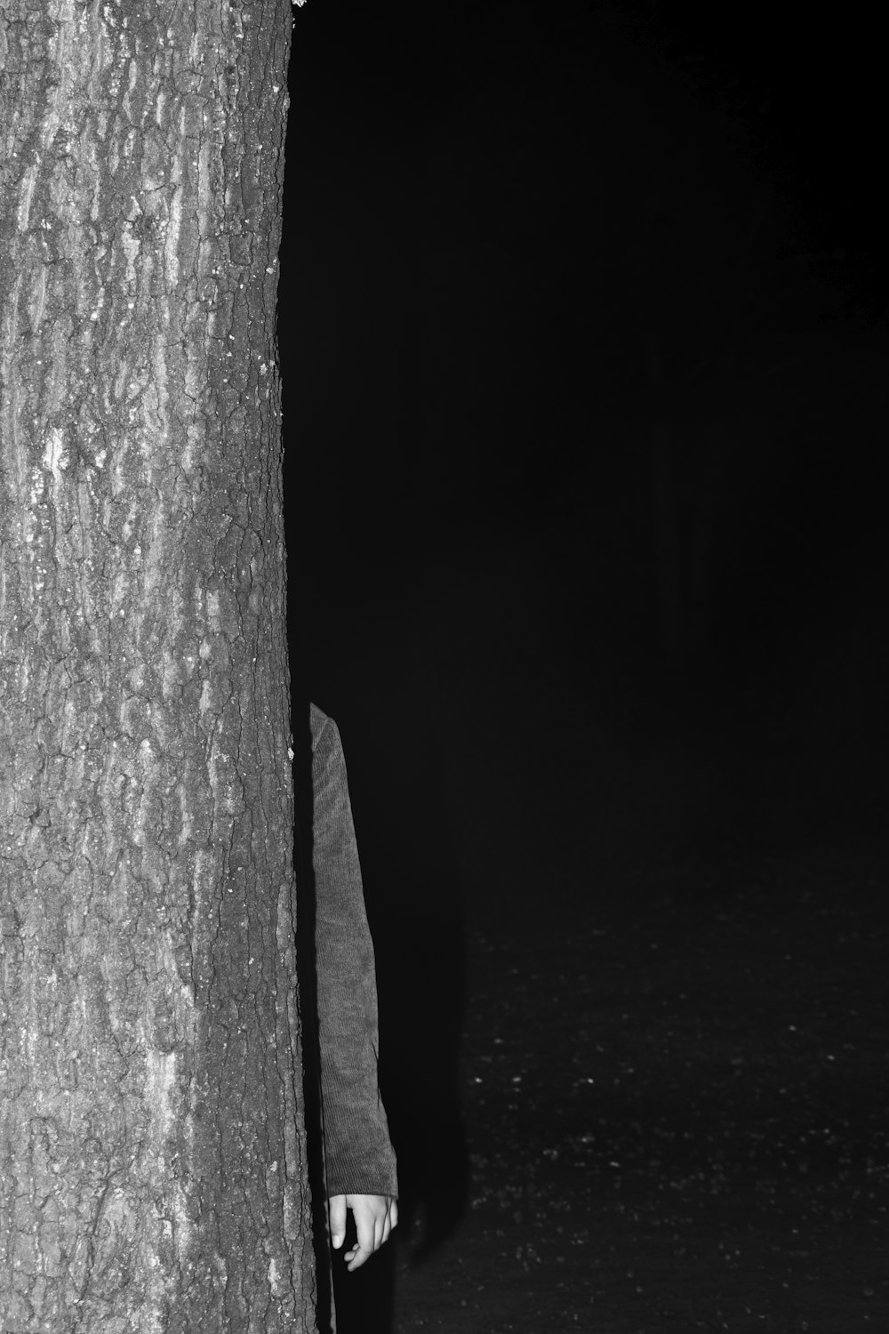 a man standing next to a tree in the dark