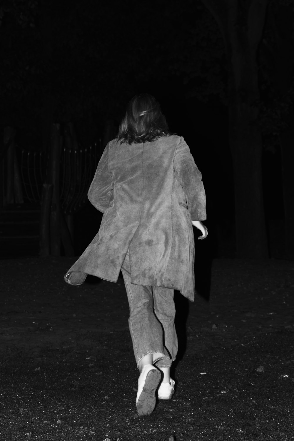 a person walking in the dark with a coat on