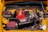 An engine bay of a car with various components visible, including a prominent red air intake filter and a large black air intake tube. The engine cover appears metallic and there are numerous wires and hoses surrounding it. The vehicle's body is painted in a bright yellow color.