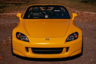 A vibrant yellow convertible parked by the dealership, catching the eye with its sporty look.