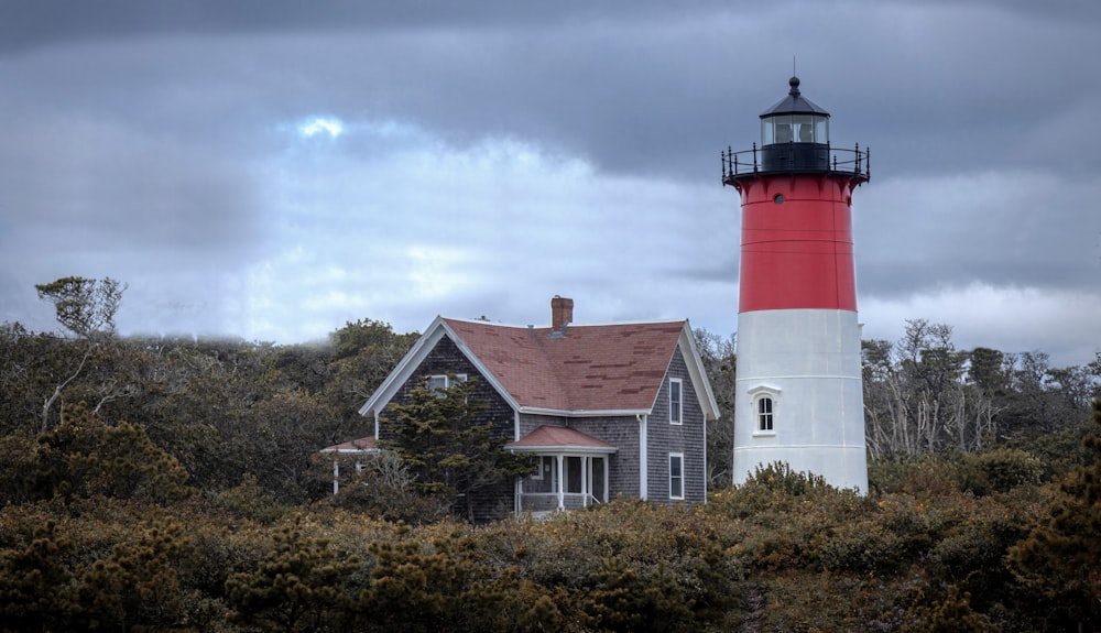 a red and white lighthouse on a cloudy day