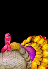 A colorful, artistic depiction of a turkey with its feathers fanned out. The body is predominantly tan with intricate patterns, while the head and neck are painted in bright shades of pink and blue. The tail feathers are vividly detailed, showcasing a gradient of yellow, red, and purple. The dark background enhances the vibrant colors, making the turkey the focal point.