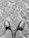 Close-up of a worn-in leather shoe paired with stylish denim on cobblestone street.