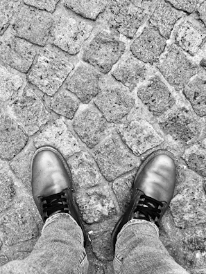 Close-up of a pair of magenta leather shoes on a cobblestone street.