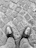 Close-up of a worn-in leather shoe paired with stylish denim on cobblestone street.