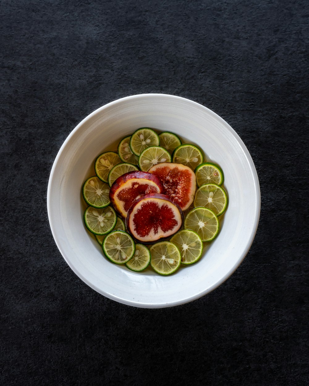 a white bowl filled with sliced fruit on top of a table