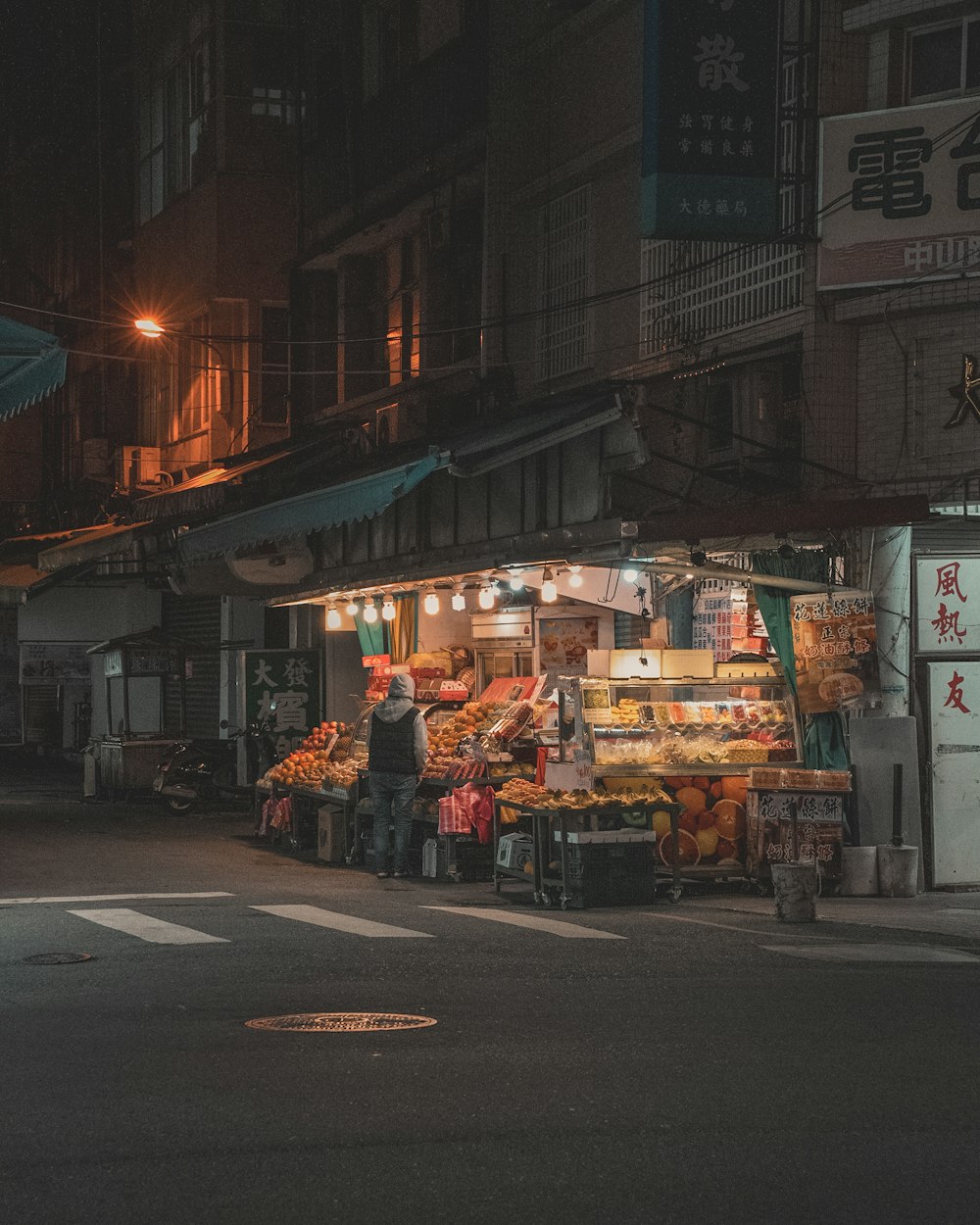 a man standing in front of a fruit stand at night