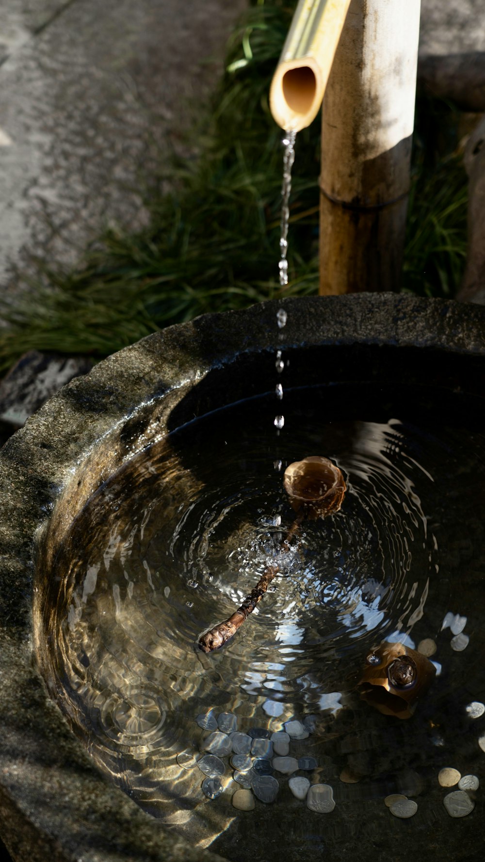 a water fountain with a bamboo stick sticking out of it