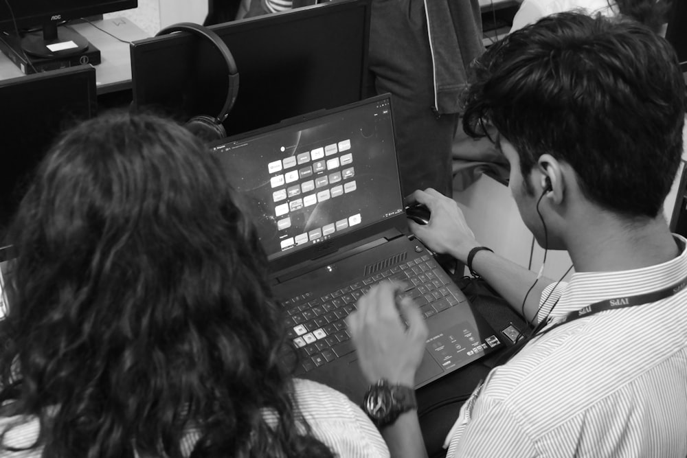 a man and a woman sitting in front of a laptop computer