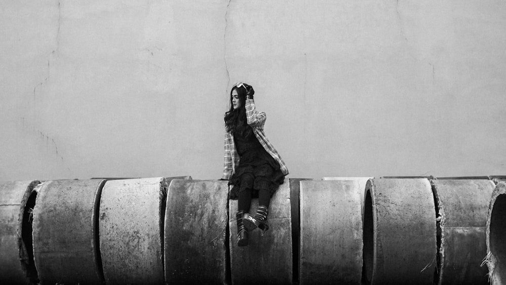 a person sitting on top of a barrel next to a wall