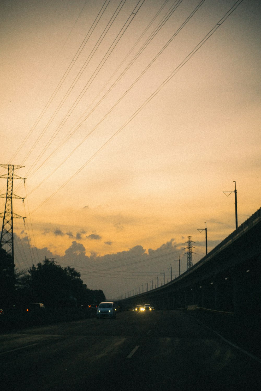 a car driving down a road under power lines