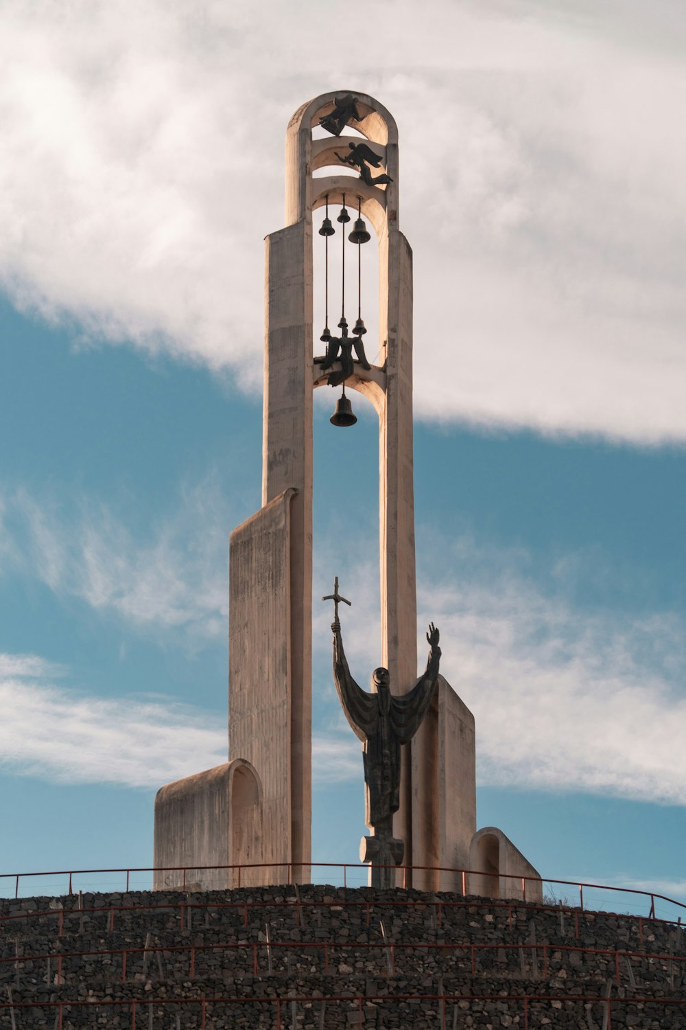 a tall clock tower with a statue of a person holding a cross