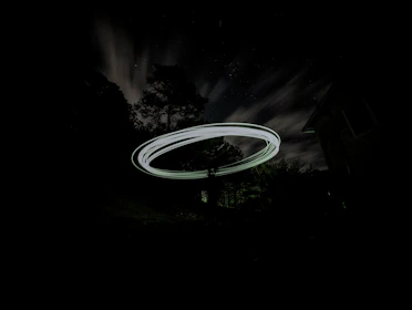 Close-up of a mysterious glowing orb hovering silently over a forest at night.