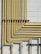 A series of yellow pipes run vertically and horizontally against a light gray concrete block wall, creating a grid-like pattern. The pipes are evenly spaced and neatly arranged, showcasing a structured and industrial design.