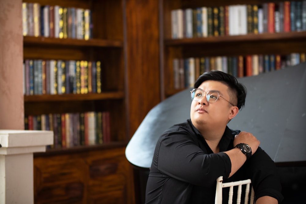 a man sitting in a chair in front of a bookshelf