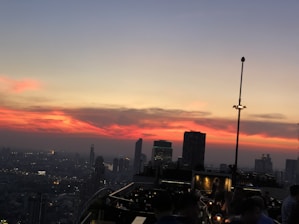 A warm sunset view over the NYC skyline from ruz bar's rooftop, with patrons enjoying cocktails.