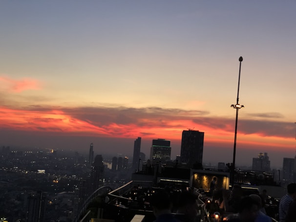A vibrant city skyline viewed from a popular rooftop bar at sunset.