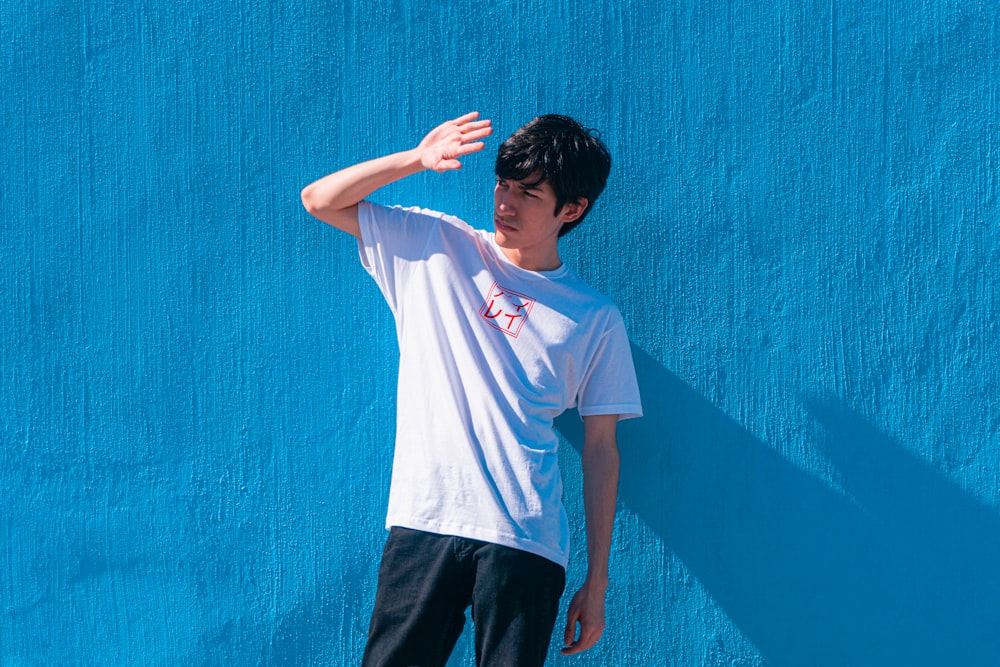 a young man standing in front of a blue wall