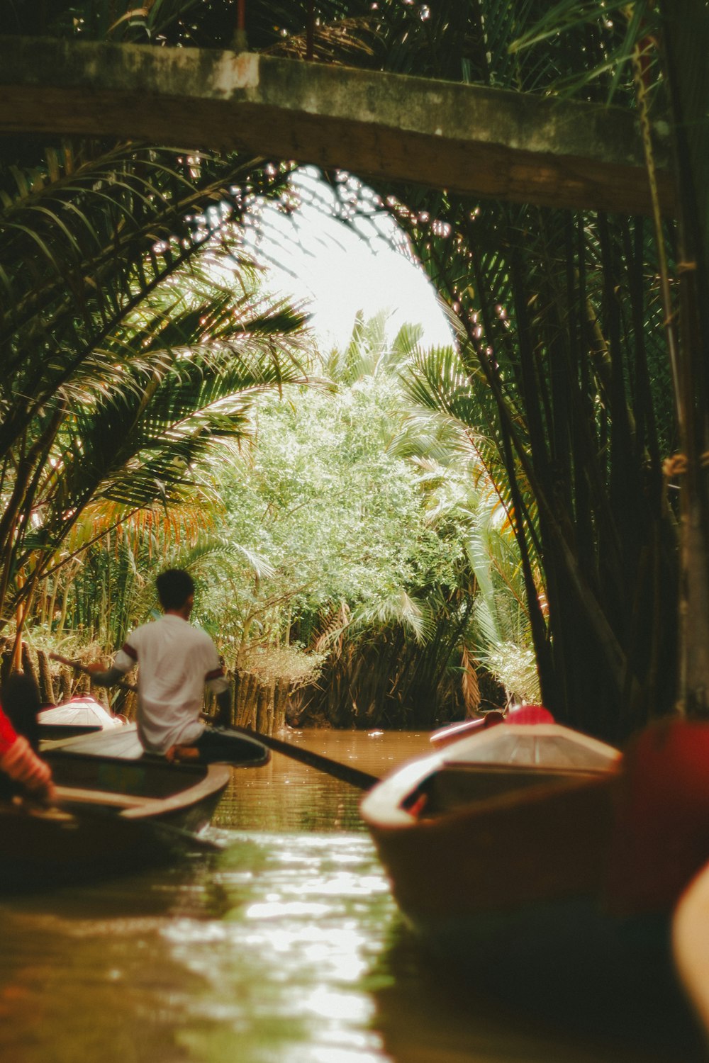 a man riding a boat down a river under a bridge