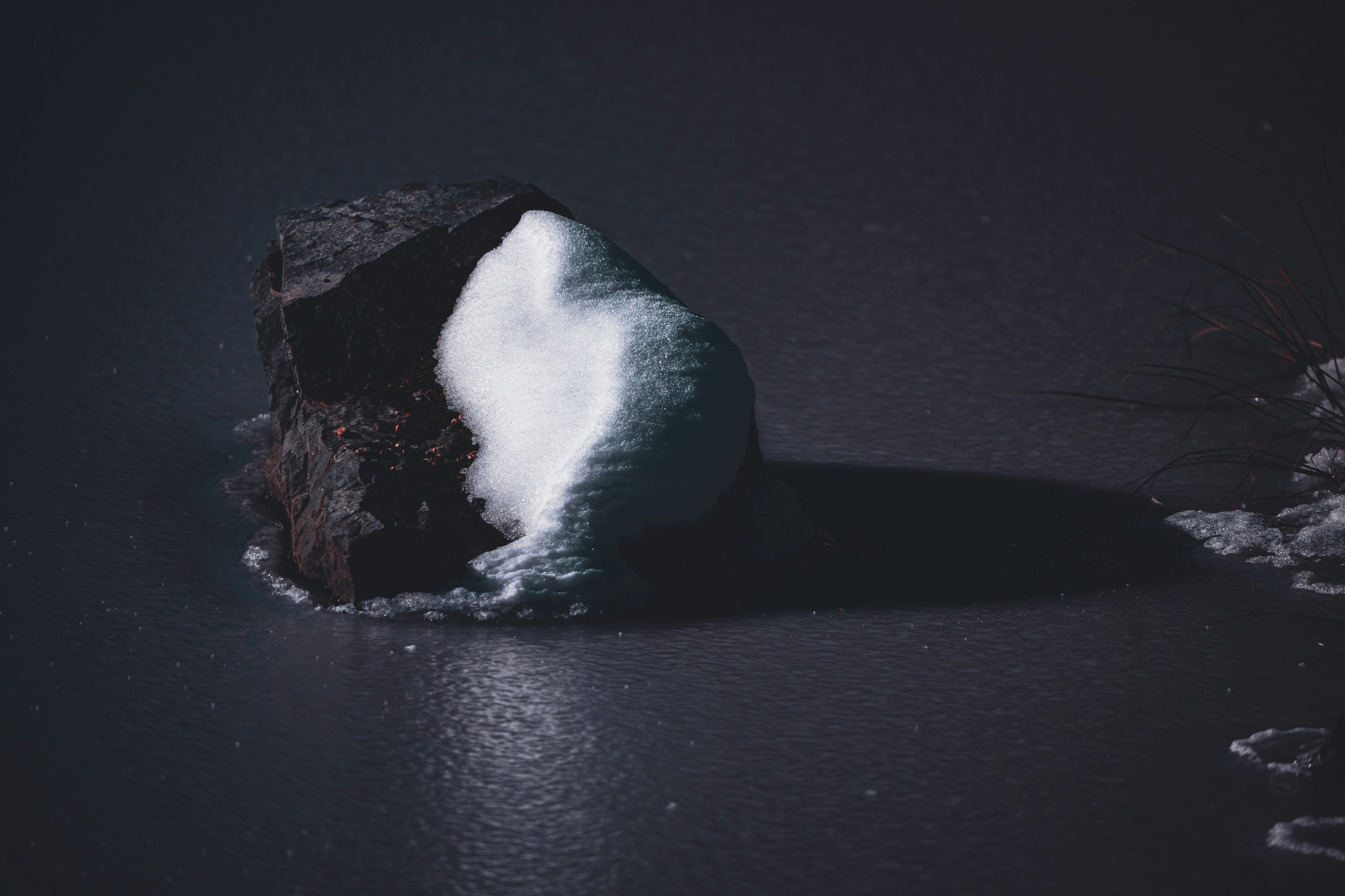 a rock covered in snow on a black surface