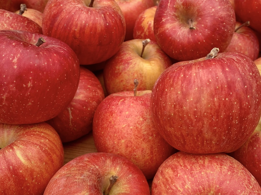 a pile of red apples sitting on top of each other