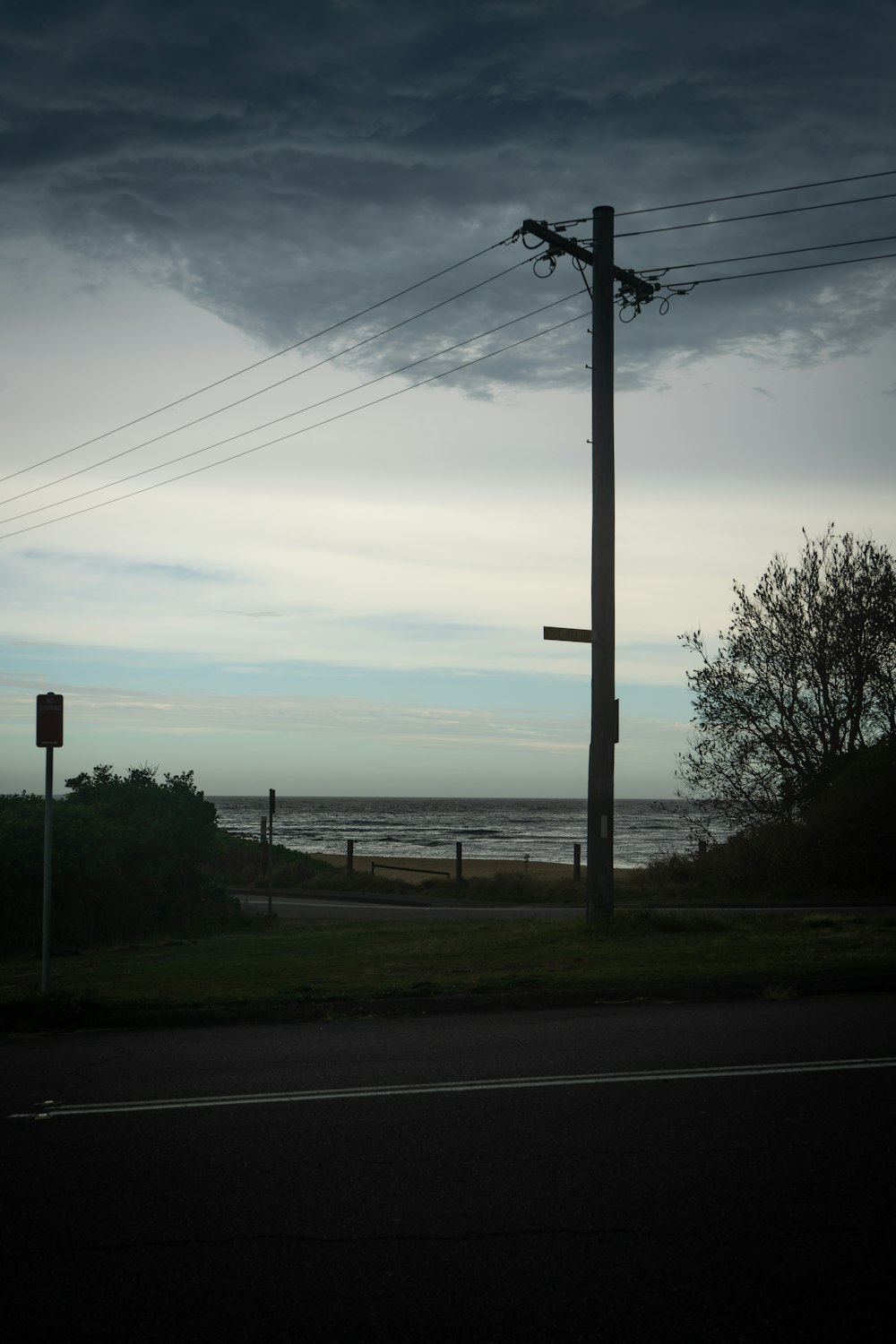 a telephone pole on the side of a road next to the ocean