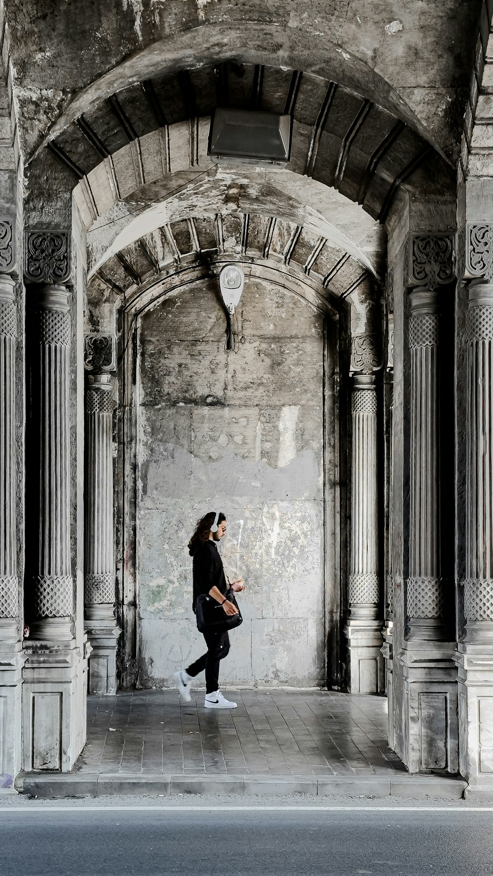 a woman walking down a street under an archway