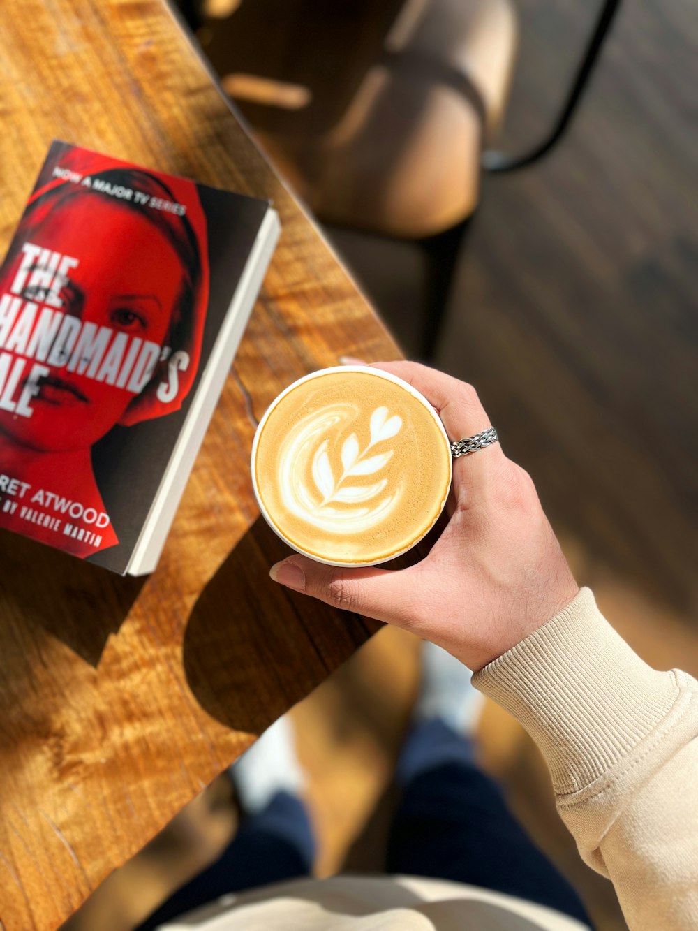 a person holding a cup of coffee in front of a book