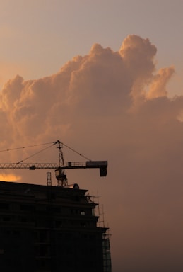 A construction crane lifting materials at a worksite during sunset.