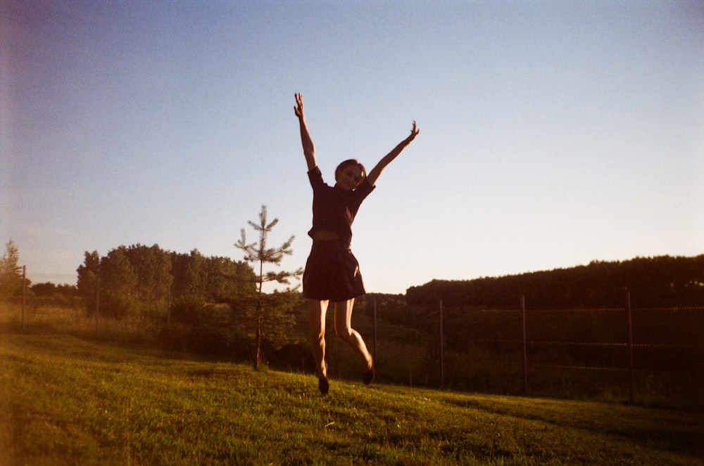 a woman jumping in the air in a grassy field