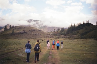 A group of players exploring a lush Minecraft landscape with mountains and trees.